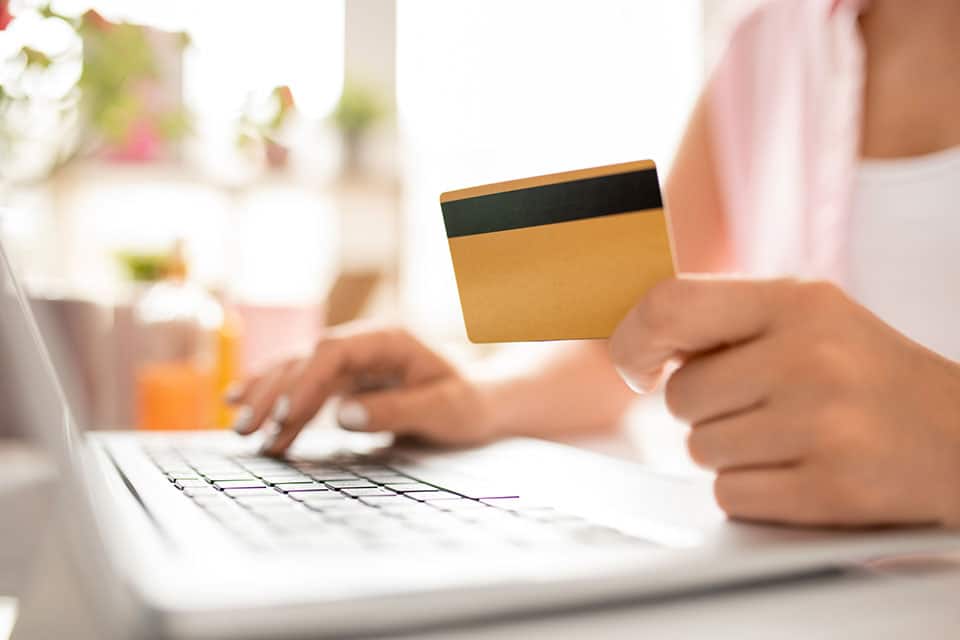 Frau mit Kundenkarte beim Online Bezahlen